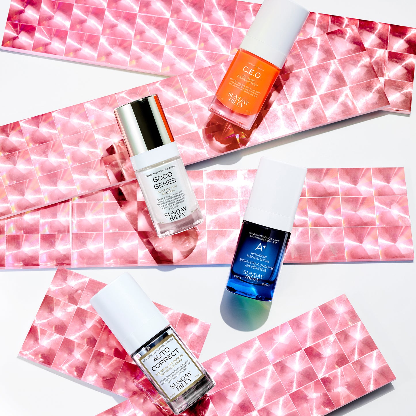 All four products laid out on a pink reflective ribbons: C.E.O Serum, Good Genes Glycolic Acid Treatment, A+ High Dose Retinoid Serum, Auto Correct