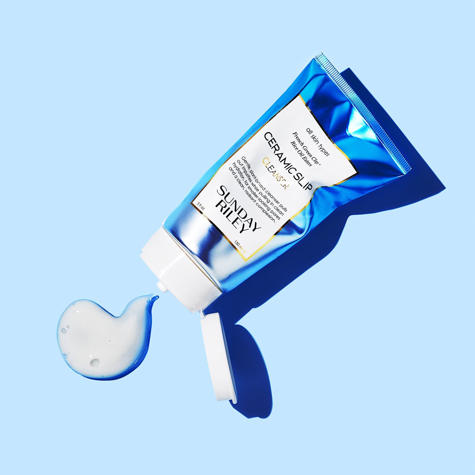 Light blue background, crushed Ceramic Slip tube, white goop spilling out