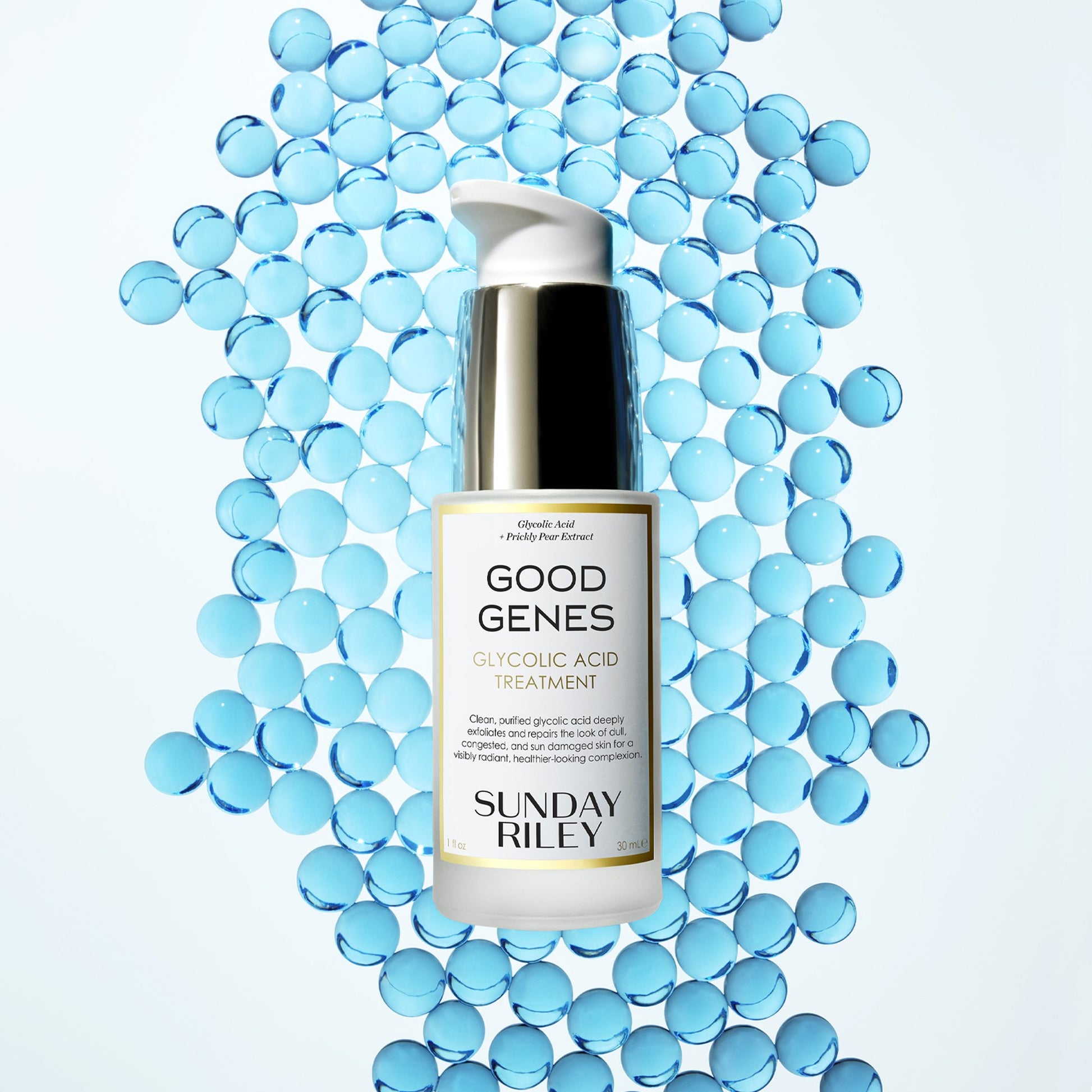 A Good Genes Glycolic frosted glass bottle with gold cap and white pump in a 30 mL bottle lay down on light blue marbles.