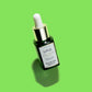 A tilted U.F.O. Ultra-Clarifying Face Oil in a green gradient glass bottle with silicon dropper with a lime green background.