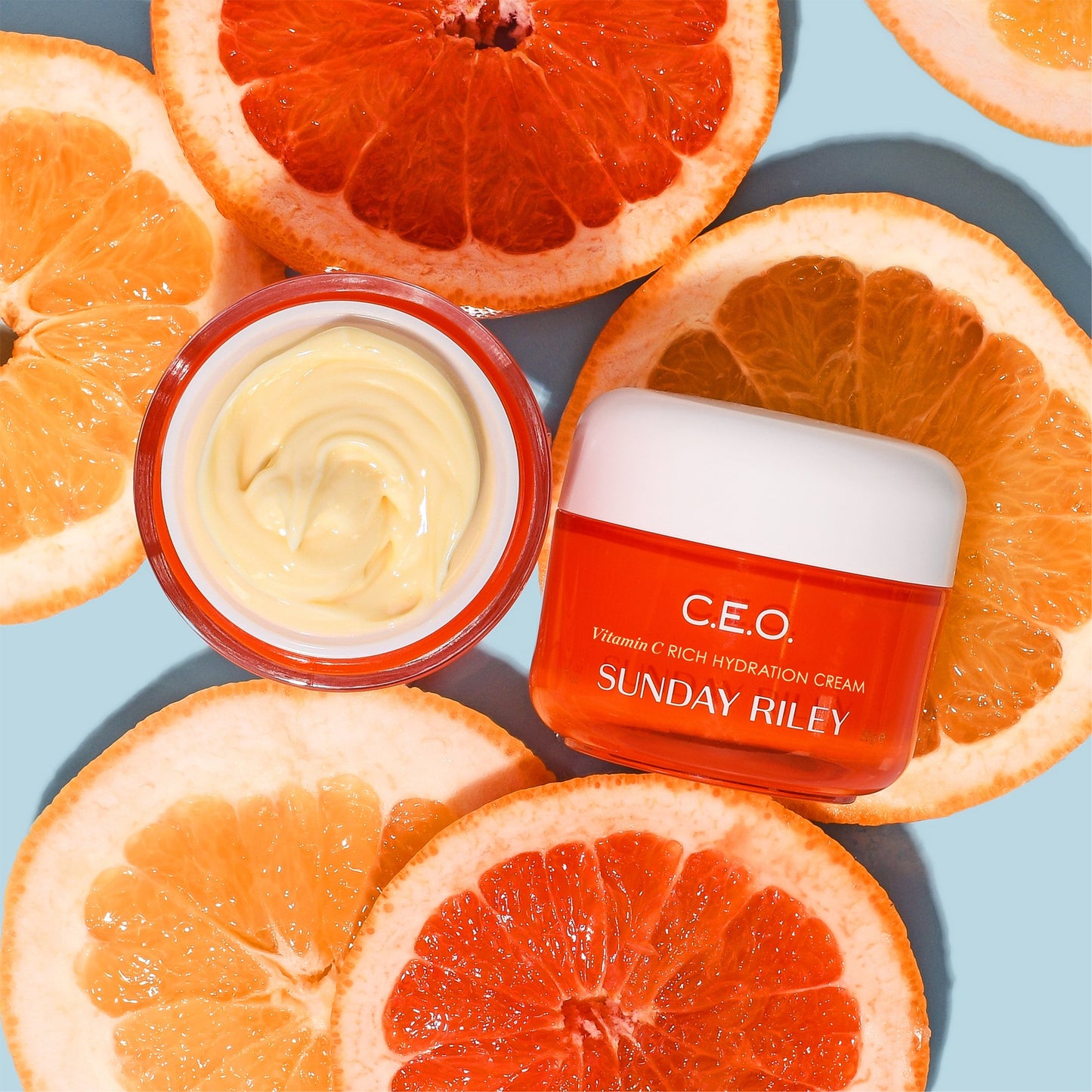 C.E.O. Vitamin C Cream lay over citric slices on light blue background