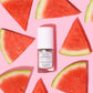 Auto Correct bottle centralized on a light pink background with watermelon slices around it