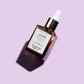 light violet background, Juno Superfood face oil glass bottle